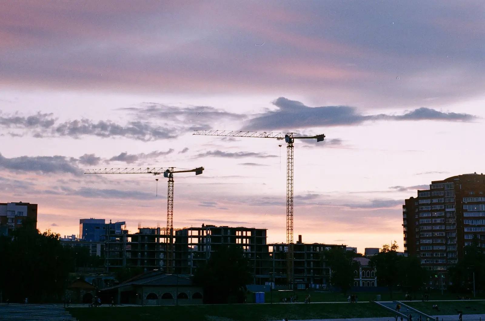 Tower cranes over a city construction site at dusk